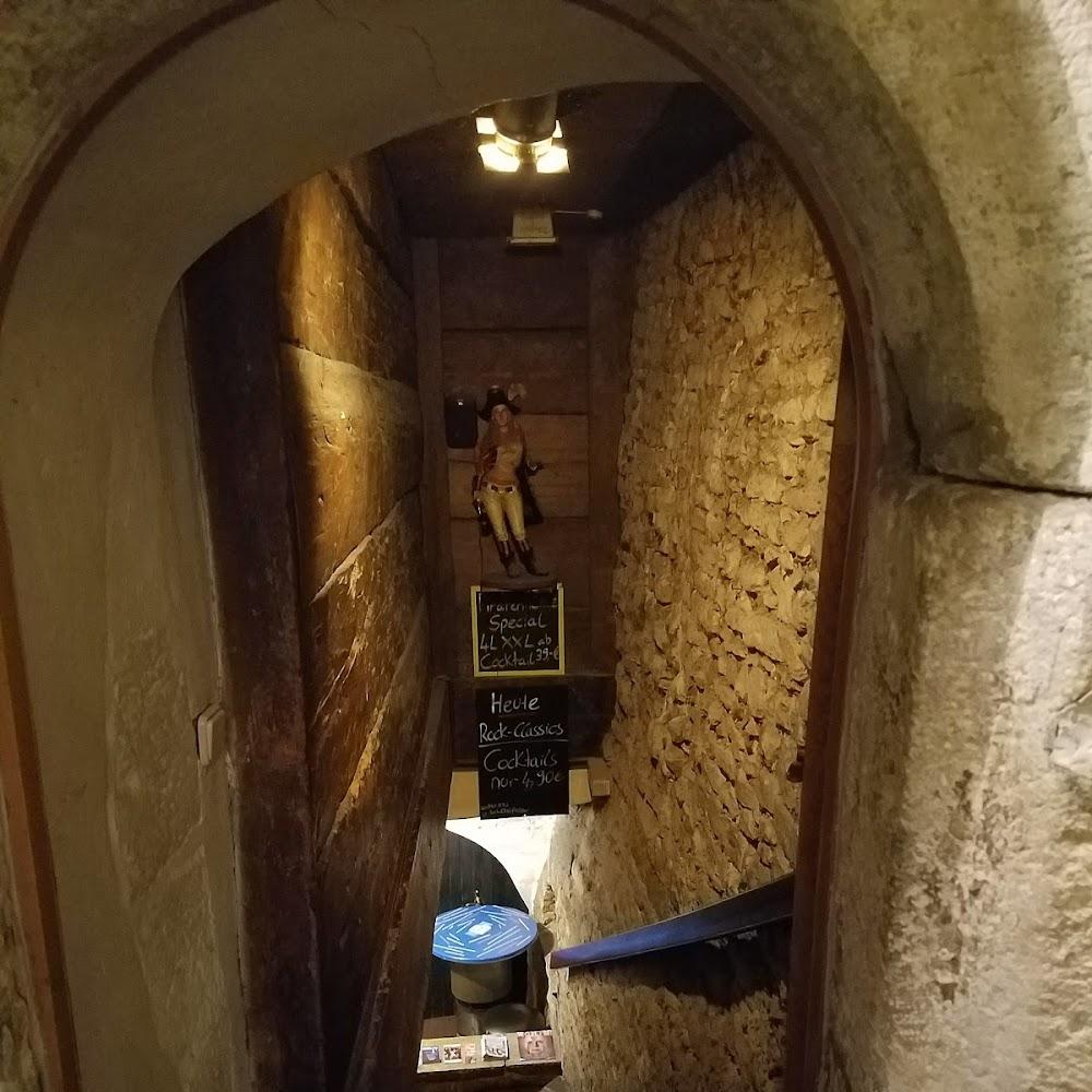 A narrow stone stairway with signs in a bar.